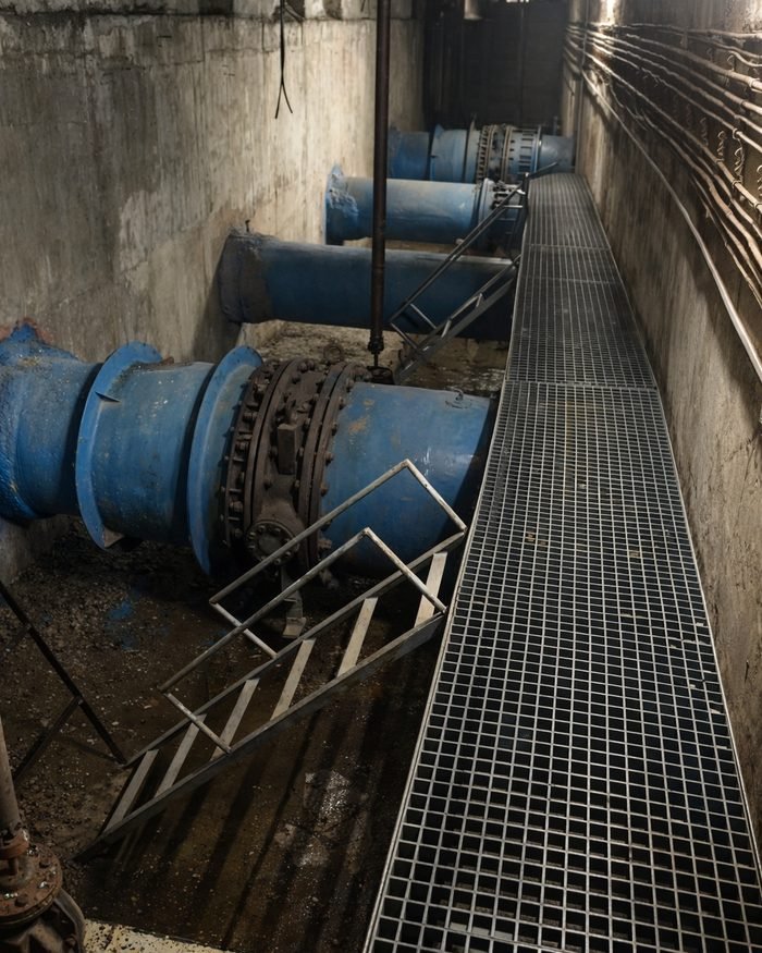 Large-diameter pump house pipework with grated walkways.
